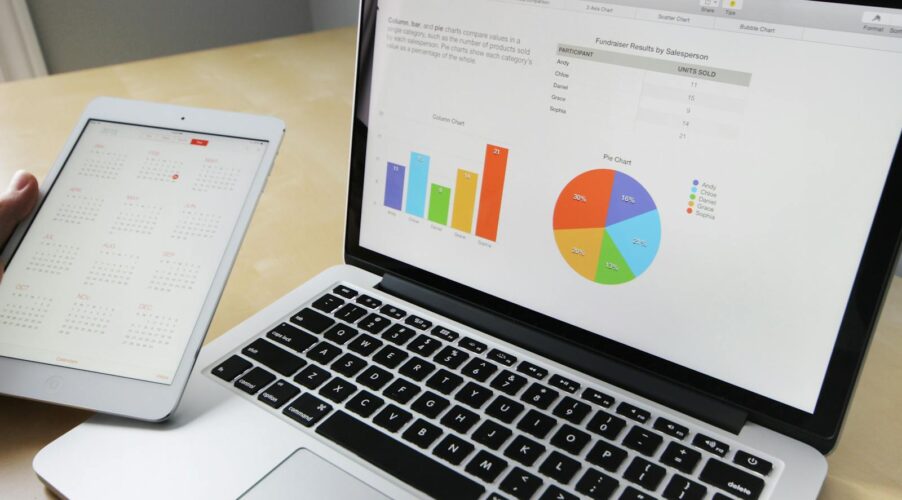 Laptop displaying charts and graphs with tablet calendar for data analysis and planning.