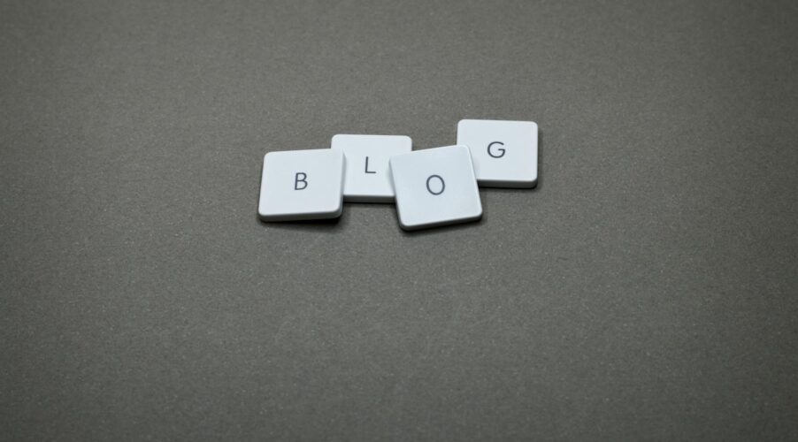 White Scrabble tiles spelling 'Blog' against a minimalist gray background.