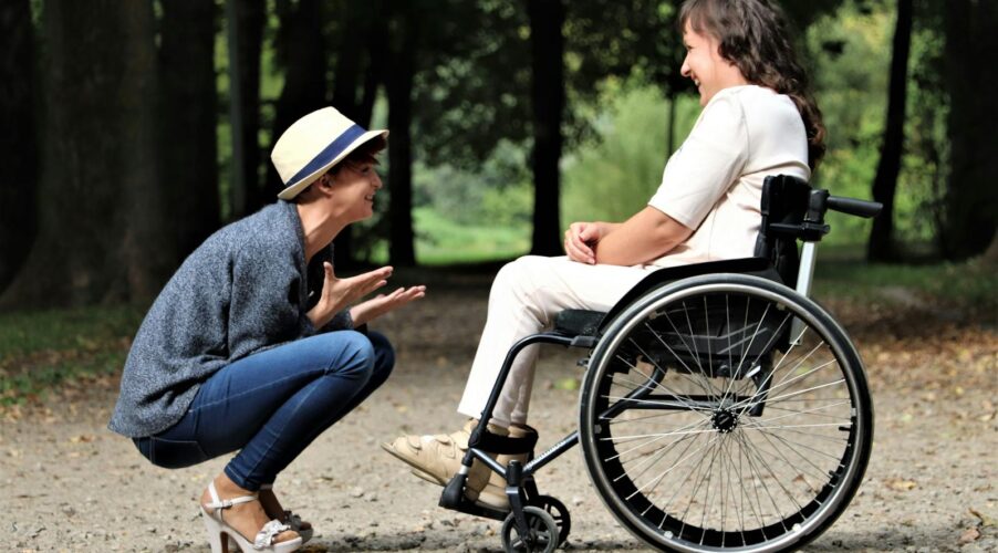 Two women enjoy a lively conversation in a sunny park, embracing friendship and happiness.