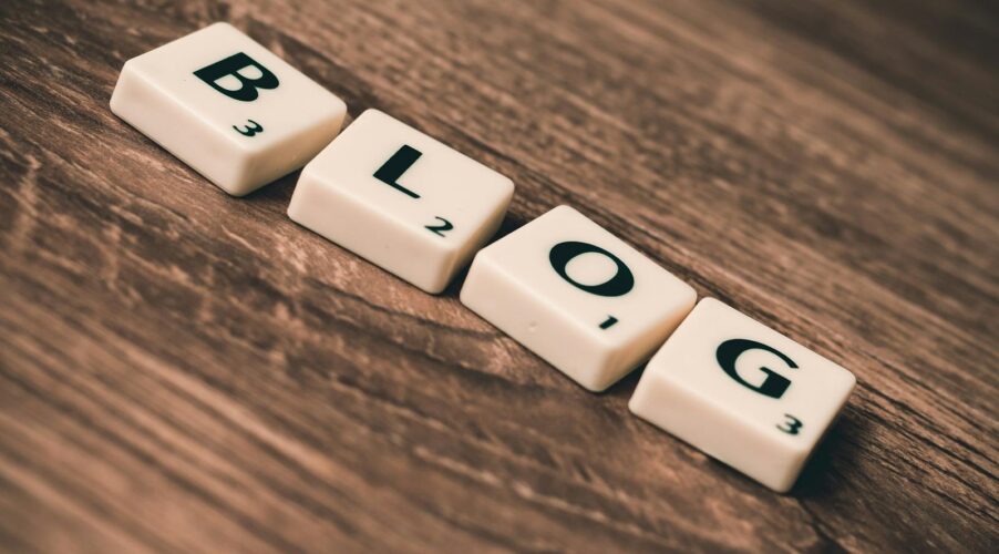 Scrabble tiles spelling 'BLOG' on a wooden background, symbolizing creativity and writing.