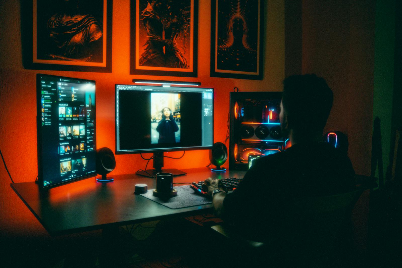 A person editing photos at night in a neon-lit home office with dual screens.