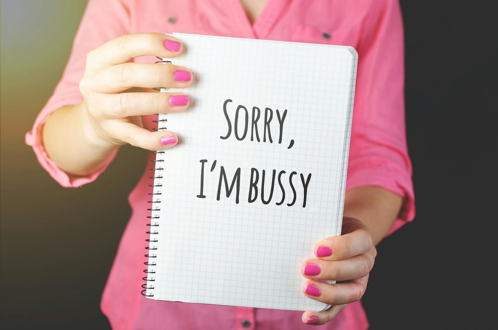 Woman holding a notebook with a handwritten message featuring a spelling error, showcasing humor and communication.